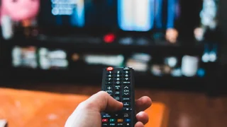 Comando apontado a um ecrã com conteúdos de televisão.