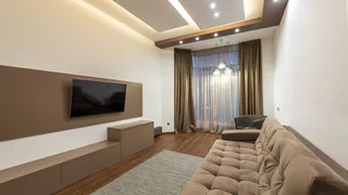 Televisor com o ecrã apagado, montado na parede de uma sala.